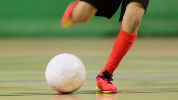 Kid plays football soccer futsal in the the sports hall